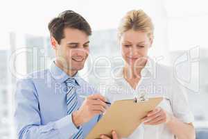 Smiling business team looking at clipboard together