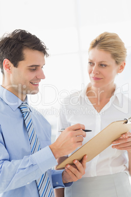 Smiling business team working from clipboard together