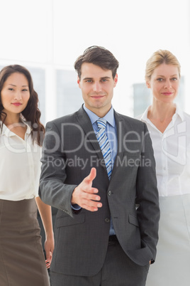 Businessman reaching hand out in front of his team