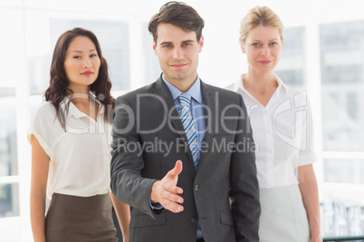 Happy businessman reaching hand out in front of his team