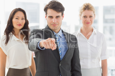 Happy businessman pointing to camera in front of his team