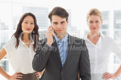 Smiling businessman on the phone in front of his team