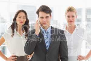 Smiling businessman on the phone in front of his team