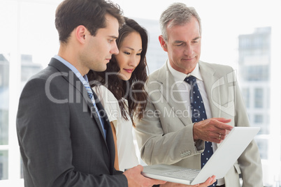 Business team looking at laptop together Business team looking at laptop together