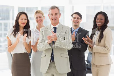 Business team standing and clapping at the camera Business team standing and clapping at the camera