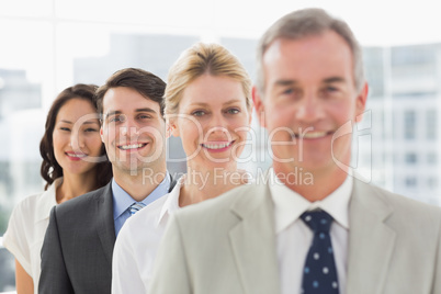 Cheerful business team standing in a line smiling at camera