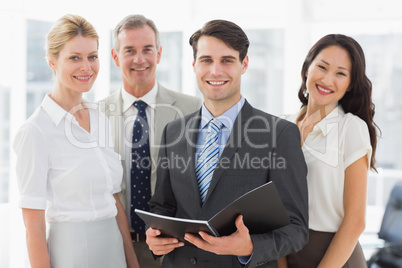 Businessman holding document smiling at camera with his team