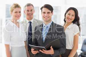 Businessman holding document smiling at camera with his team