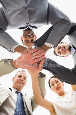 Business team smiling down at the camera with hands together