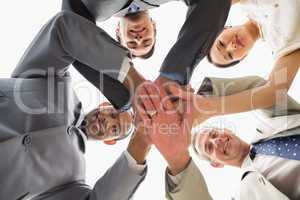 Business team looking down at the camera with hands together