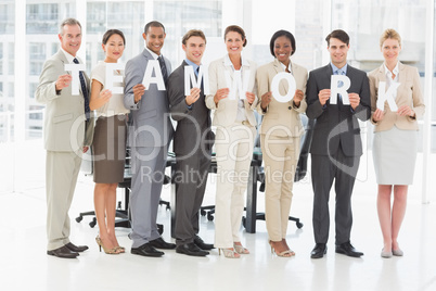 Diverse business team holding up letters spelling teamwork