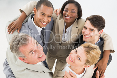Close business team embracing in a circle smiling up at camera