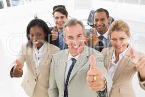 Diverse close business team smiling up at camera giving thumbs u