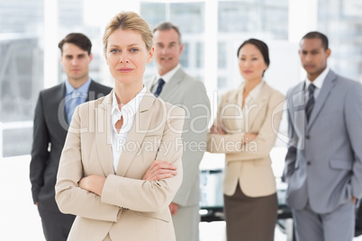 Businesswoman looking at camera with team behind her Businesswoman looking at camera with team behind her