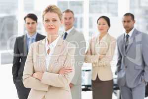 Businesswoman looking at camera with team behind her