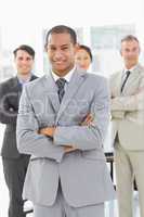 Businessman smiling at camera with team behind him