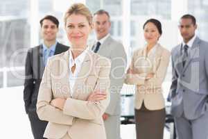 Businesswoman smiling at camera with team behind her