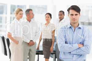 Stern businessman standing with team behind him