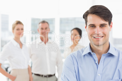 Smiling businessman standing with team behind him