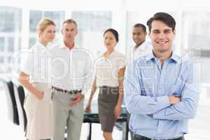 Happy businessman standing with team behind him