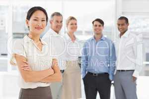 Smiling businesswoman standing with team behind her