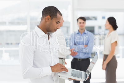 Young businessman using laptop with team behind him