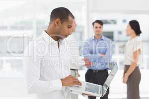 Young businessman using laptop with team behind him