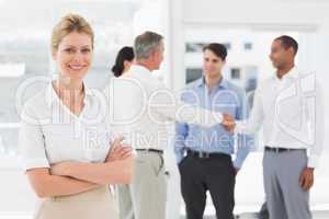 Blonde businesswoman with team behind her smiling at camera