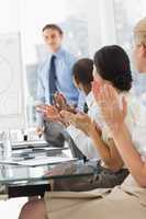 Businessman being applauded by colleagues for his presentation