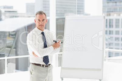 Stern businessman standing at whiteboard with marker