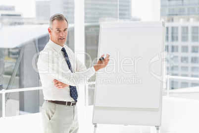 Smiling businessman presenting at whiteboard with marker