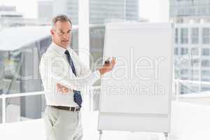 Smiling businessman presenting at whiteboard with marker