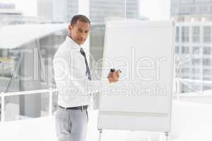 Young businessman presenting at whiteboard with marker