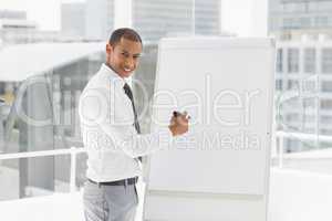 Young happy businessman presenting at whiteboard with marker