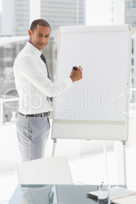 Young smiling businessman presenting at whiteboard with marker