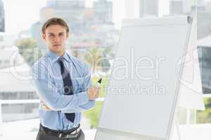 Young stern businessman standing by whiteboard