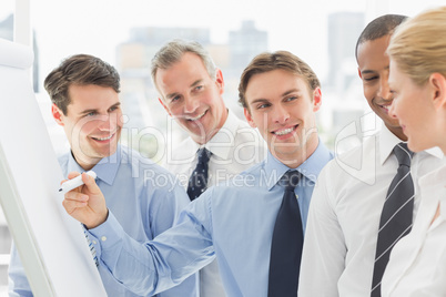 Young businessman writing on whiteboard with colleagues