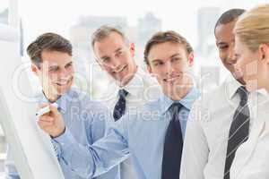 Young businessman writing on whiteboard with colleagues