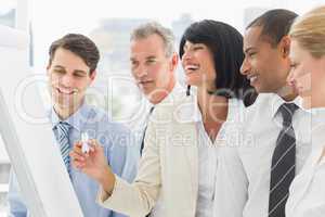 Colleagues watching laughing businesswoman write on whiteboard