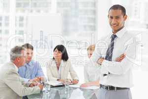 Young businessman looking at camera while staff discuss behind h