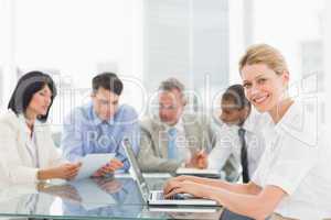 Businesswoman using her laptop during a meeting smiling at camer