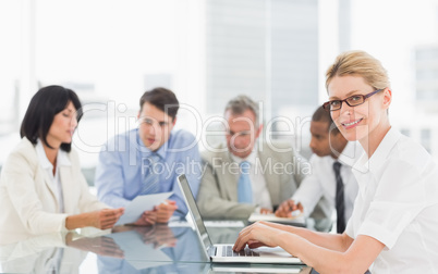 Businesswoman using her laptop during a meeting looking at camer