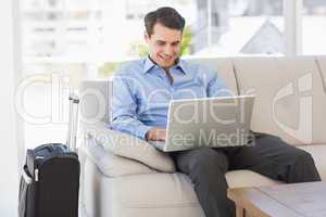 Travelling businessman using laptop sitting on the couch
