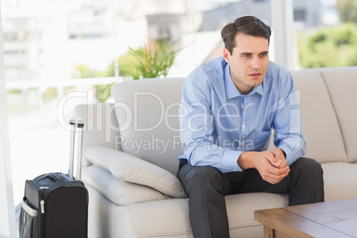 Businessman sitting on couch waiting to leave on business trip