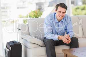 Smiling businessman sitting on couch waiting to leave on busines