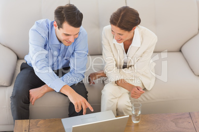 Business partners working on laptop sitting on sofa