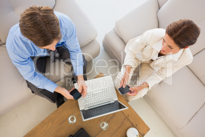 Business team working together on the couch using their smartpho