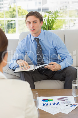 Businessman scheduling with colleague sitting on sofa