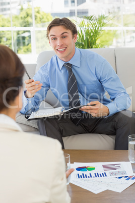 Happy businessman scheduling with colleague sitting on sofa