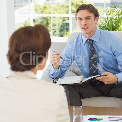 Young businessman scheduling with colleague sitting on couch